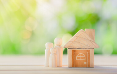 Obraz na płótnie Canvas Wooden home with happy family of wooden doll is placed inside on nature bokeh. The saving money for house or real estate owner in the future concept. concept for property, mortgage and investment.