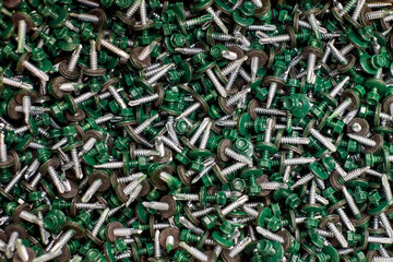 Bunch of galvanized self-drilling screws with washer and green hexagonal head, hardware background