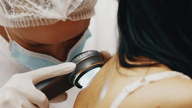 Close-up of dermatologist checking woman's birthmark.