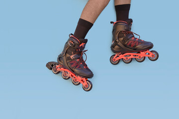 Two legs of boy with inline skates on blue background with copyspace