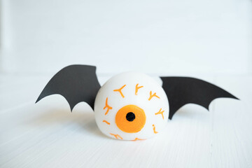 toy eyes with bat wings on a white wooden background, place for text , abstract Halloween concept
