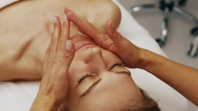 A young woman receives a facial massage from a beautician. Skin care.
