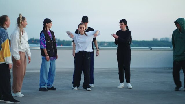 dance of teens in hip-hop party on roof, young b-girl is performing toprock and cool b-boy downrock
