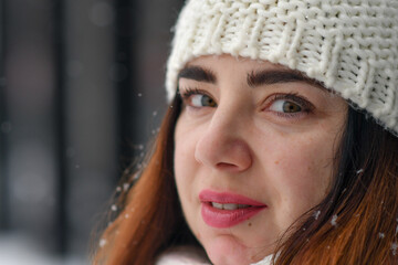 Close up portrait of romantic caucasian woman with ginger hair at winter snowfall. 