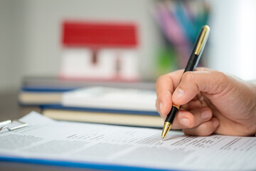 Woman home sales person is checking documents for house purchase contract before letting the customer sign contract on table is key with house model, real estate trading and insurance property concept