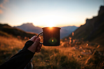 Closeup photo of cup with tea, coffee in traveler's hand over out of focus mountains view. Scenery...