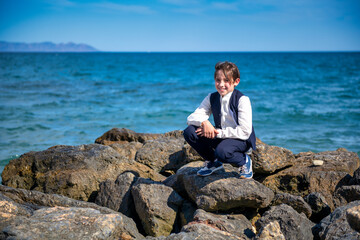 child poses on rocks with sea in background