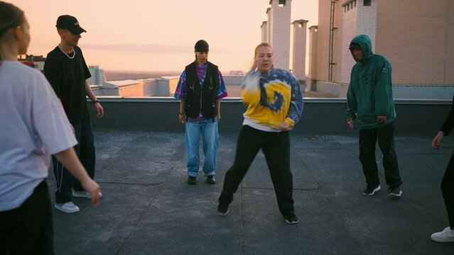 girl breakdancer is dancing in round of young dancers on roof, street dance party of youth
