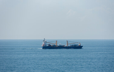 Small cargo ship sailing through the calm sea. 