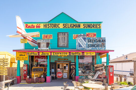 colorful facade of Shop Historic Seligman Sundries with stars and stripes and an aircraft crashed in the facade and vintage car at route 66 in Seligman, USA