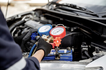 Close up hand of auto mechanic using measuring manifold gauge check the refrigerant and filling car...