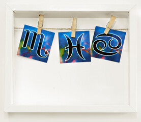 Water signs Pisces, Cancer and Scorpio, a white frame with zodiac signs hung on a clothesline with...