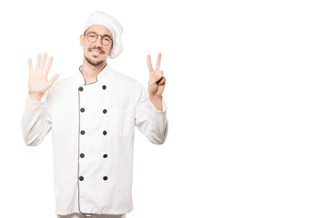 Happy young chef doing a number seven gesture with his hands