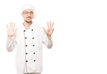 Happy young chef doing a number nine gesture with his hands