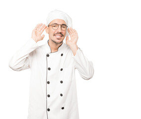 Happy young chef smiling and making a gesture of trying to hear something