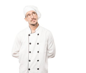 Serious young chef looking against background