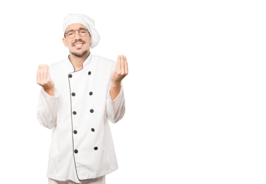Confused young chef making an italian gesture of not understand