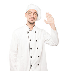 Young chef waving with his hand