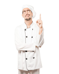 Hesitant young chef pointing up with his finger