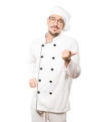 Hesitant young chef pointing at you with his finger