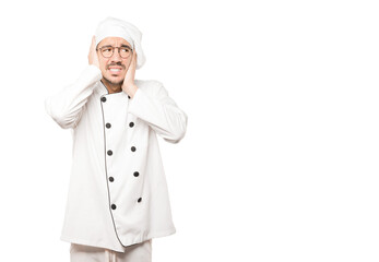 Concerned young chef worried about loud noises and covering his ears