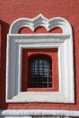 Square window with grate in a brick wall.