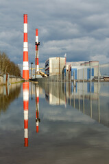 power plant reflection water sky clouds pipes fence cooling tower