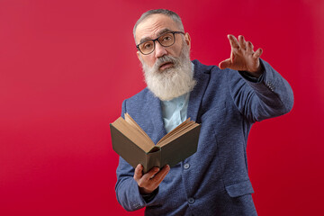 Senior litterateur, man of letters, bookman with a gray beard in a light shirt in a dark casual jacket holding a book - obrazy, fototapety, plakaty