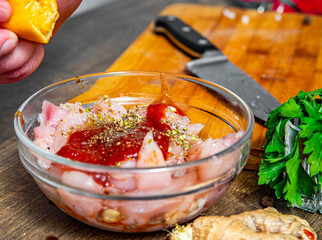 Raw marinated chicken meat with garlic, ginger and teriyaki sauce in a glass bowl on wooden table