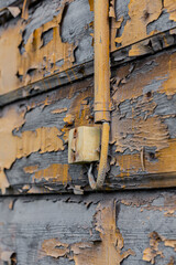 An old light switch on a wooden wall with peeling paint. Selective focus. An old switch on the wall in close-up.