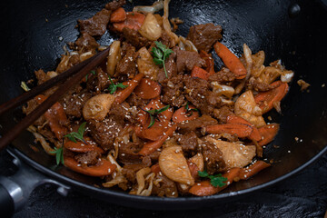 Seitan, daicon and carrot stir fry in wok on black table