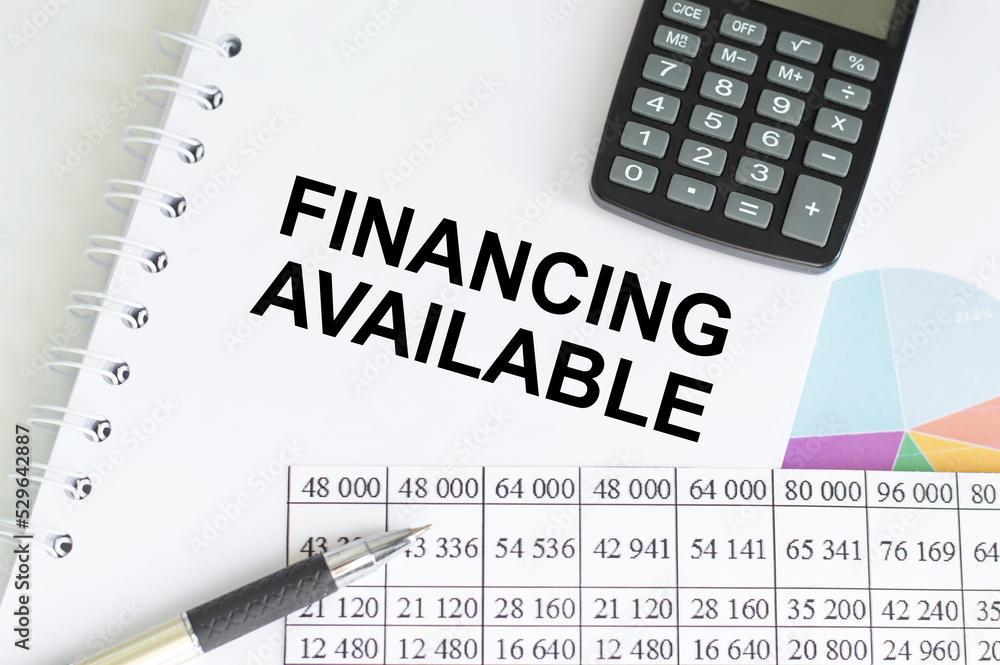 Poster financing available text on a notepad on the table next to the calculator and pen and financial repo