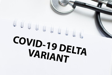 COVID-19 DELTA VARIANT inscription on a white sheet of notepad on the table next to it is a...