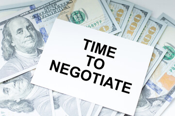 Text TIME TO NEGOTIATE on the card next to the dollar bills on the table, business and finance