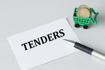 TENDERS text on a white card on the table next to the pen and coins in the basket, business concept