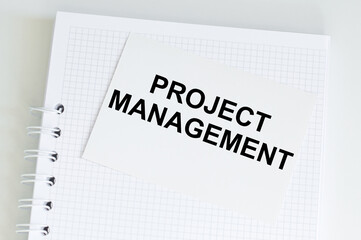 PROJECT MANAGER text on a card that lies on a notebook on a bright desk, a business concept
