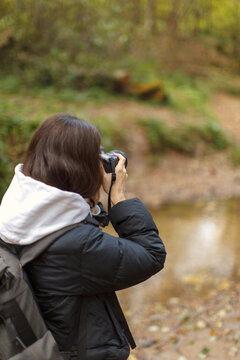 female photographer tourist in autumn forest take photo scenery