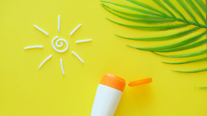 Sunscreen. Protect skin from sun. Cream sun and tube on a solid yellow background with palm branch