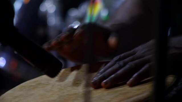 Black hands playing djembe hold between his knees in front of microphone, Abene, Casamance, Senegal, staying still.