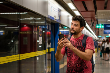 Hombre verificando su recorrido en subte en una aplicación de su celular - obrazy, fototapety, plakaty