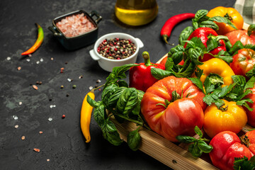 Various colorful garden tomatoes, bell peppers and spices. Ingredients for cooking on a dark background. place for text, top view