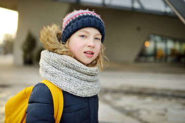 Cute young girl with a backpack heading to school on cold winter morning. Child going back to...