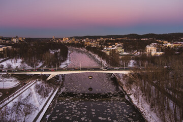 Aerial view of a bridge though Neris river in wintertime. Aerial sunset view of Vilnius city.