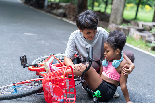  Asian mother takes care of her curly-haired half-African American daughter, trains to ride a bike in a park, falls and injured her mother came to the rescue.