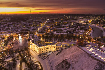 Fototapeta premium Beautiful Vilnius city panorama in winter with snow covered houses, churches and streets. Aerial evening view. Winter city scenery in Lithuania.
