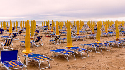 The beach at Lido di Jesolo. Lots of blue sun loungers and yellow umbrellas on the beach. Sunset . Italy