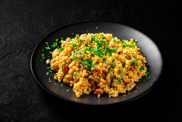 Bulgur with vegetables on black plate on Dark grey black slate background