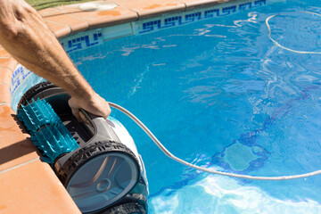 maintenance worker putting the cleaning robot into the pool water. robotic pool cleaner Pool...