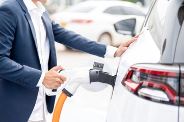 Chinese electric cars in Laos plug into electrical connectors to charge batteries Unknown man...
