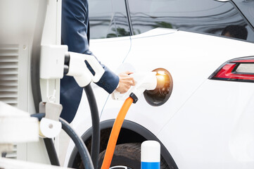 Chinese electric cars in Laos plug into electrical connectors to charge batteries Unknown man...